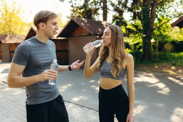 Eğitimden sonra parkta dinlenen ve su içen çift. Sağlıklı yaşam tarzı kavramı