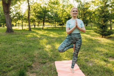 Park 'ta yoga yapan son sınıf öğrencisi bir kadın. Sağlıklı yaşam tarzı kavramı.