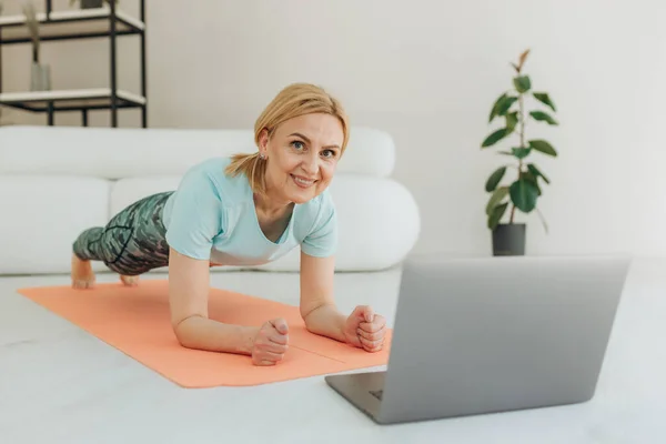 Sportig Medelålders Kaukasiska Kvinna Stående Planka Position Med Hjälp Laptop — Stockfoto