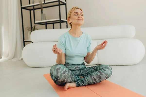 Olgun kadın evde yoga yapıyor..