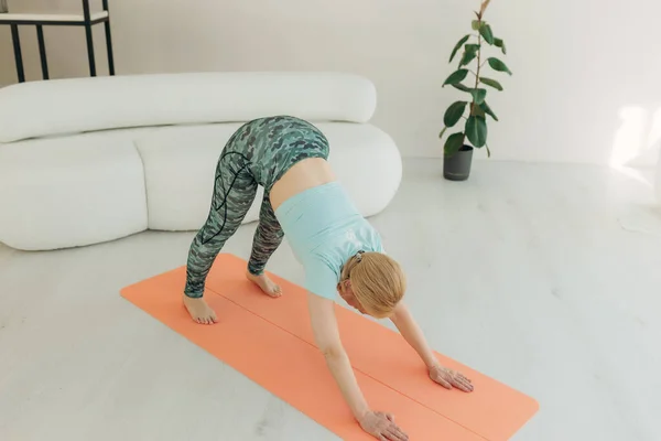 老年妇女在她家客厅里做瑜伽 健康生活方式的概念 在家培训 — 图库照片