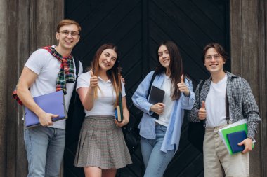 Group portrait of multiracial smiling students with books and backpacks looking at camera. Education concept