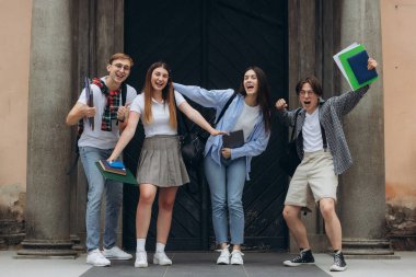 Group portrait of multiracial smiling students with books and backpacks looking at camera. Education concept