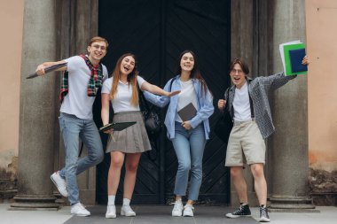 Group portrait of multiracial smiling students with books and backpacks looking at camera. Education concept