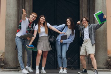 Group portrait of multiracial smiling students with books and backpacks looking at camera. Education concept