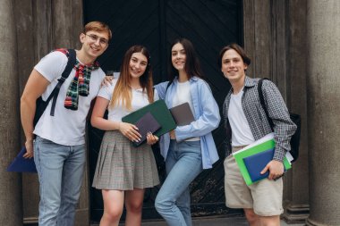 Group portrait of smiling students with books and backpacks looking at camera. Education concept