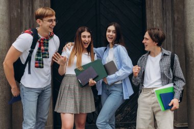 Group portrait of smiling students with books and backpacks looking at camera. Education concept