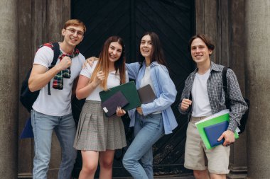 Group portrait of multiracial smiling students with books and backpacks looking at camera. Education concept