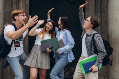 Group of smiling students with raised hands. Happy friends