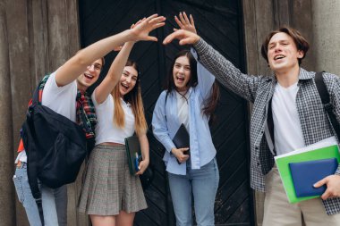 Group of students standing in a circle with hands raised in the air