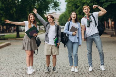 Group of teenage students standing outdoors. Friends are smiling and happy