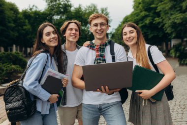Group of happy smiling students Outside College looking excited in laptop