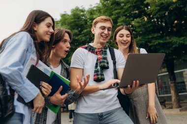 Group of happy smiling students Outside College looking excited in laptop