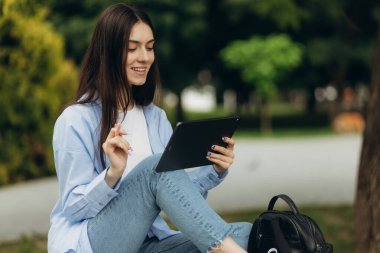 closeup of happy young girl in using tablet pc in the park