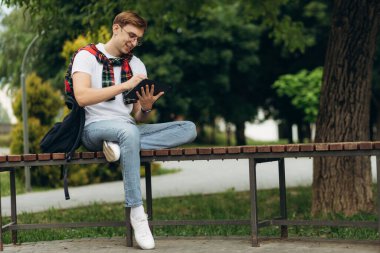Happy smiling student outdoors with tablet. Emotion of joy. The concept of college education