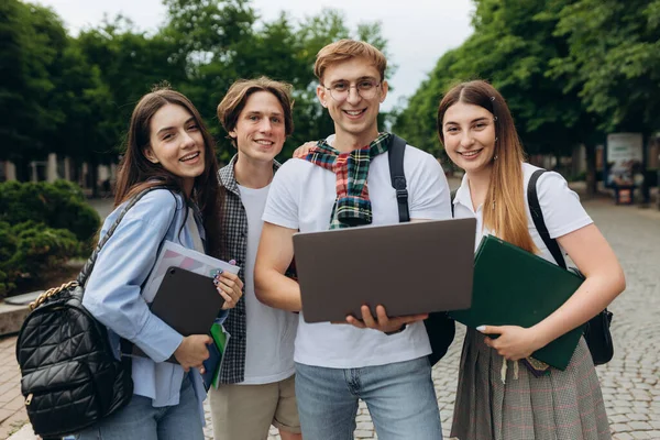 Group of happy smiling students Outside College looking excited in laptop