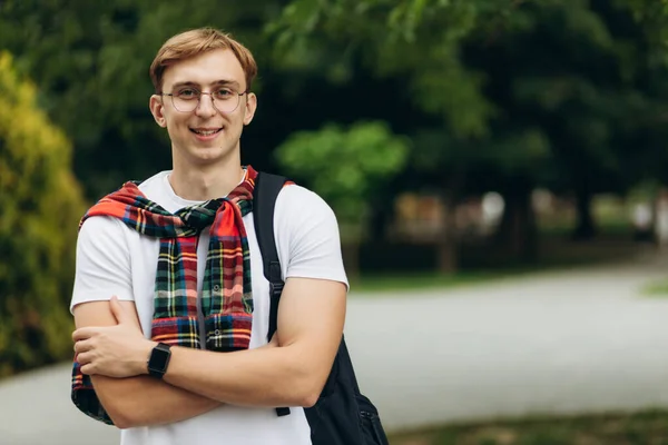 portrait of an attractive guy in student glasses with a backpack. Learning concept. Cope space