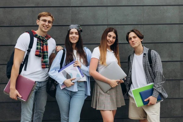 Portrait of smiling young diverse students standing in a row on the wall. College concept