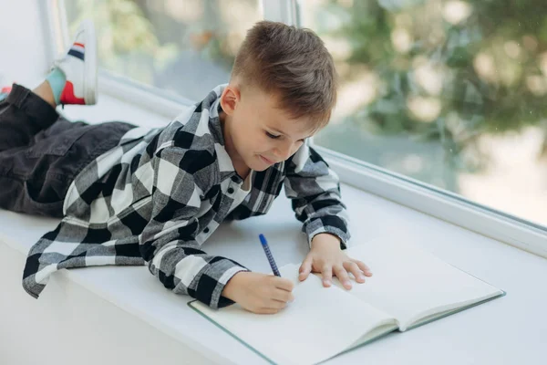 Μικρός Διαβάζει Αγόρι Κείτεται Στο Περβάζι Του Παραθύρου Και Γράφει — Φωτογραφία Αρχείου