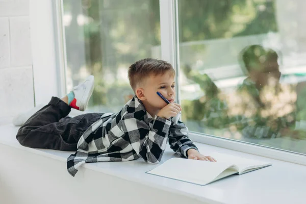 Μικρός Διαβάζει Αγόρι Κείτεται Στο Περβάζι Του Παραθύρου Και Γράφει — Φωτογραφία Αρχείου