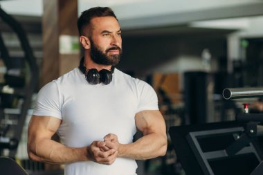 Athletic man in a white shirt shows off his muscles in the gym