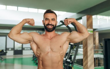 Muscular man in gym. Fitness men with naked torso show his biceps.