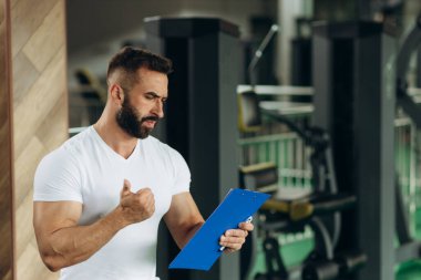 Young coach making a training plan in a gym. Copy space
