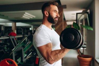 Ağırlık kaldıran yakışıklı halterci spor salonunda halterle çalışıyor.