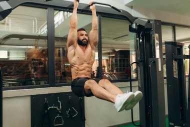 Muscular guy is training on the horizontal bar in gym