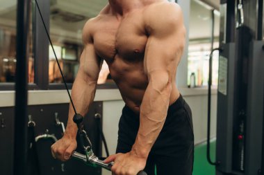 Close-up of man doing exercises on muscles of triceps in simulator. Muscles on arms, ligaments. Concept workout, bodybuilder in gym