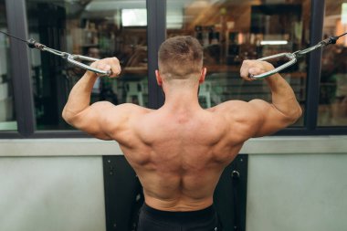 Man doing exercises on the simulator. Back view