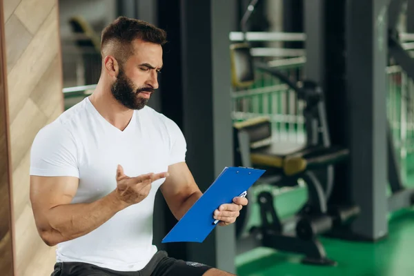 Young coach making a training plan in a gym. Copy space