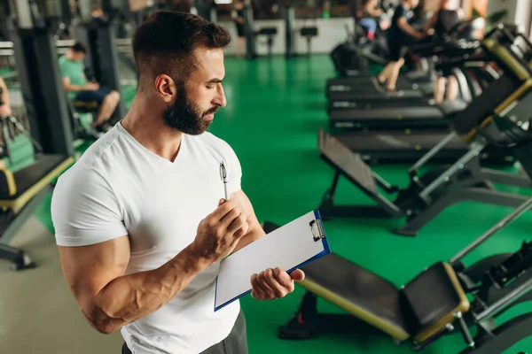 Young coach making a training plan in a gym. Copy space