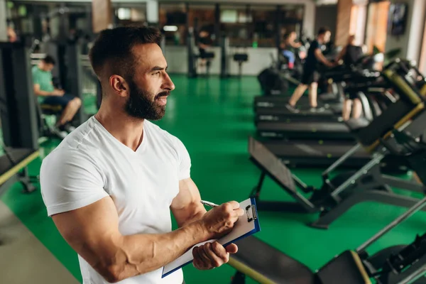 Young coach making a training plan in a gym. Copy space