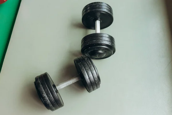 Black desk of free space for your decoration and blurred gym interior.Metal dumbbells and fit life