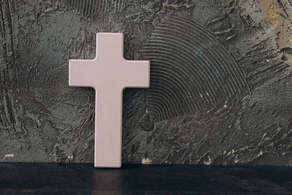 Christian cross on a textured black background. Religion concept. Pink cross