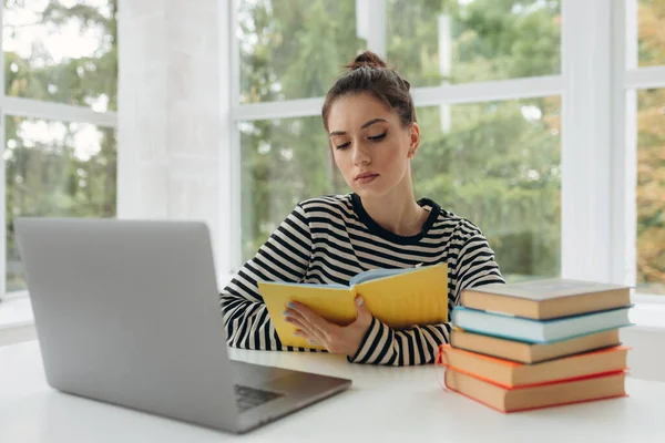 Beautiful student studying online and learning writing notes in a desk at home