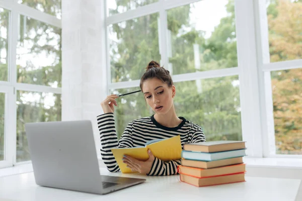 college student doing some home works from home with laptop