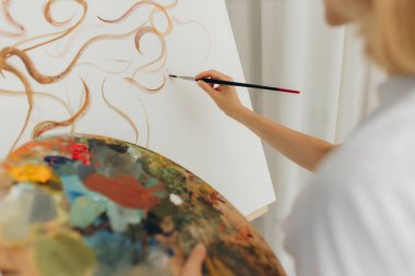 Close-up artist paints oil painting on canvas.