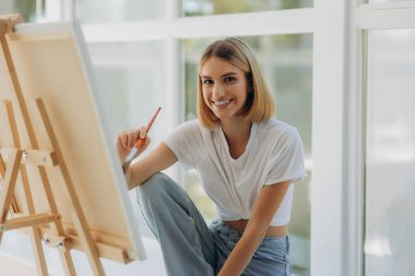 Beautiful artist in her studio. Happy girl likes to draw.