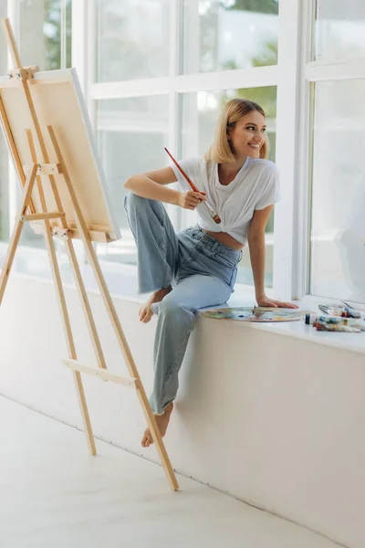Beautiful artist in her studio. Happy girl likes to draw. Place for text