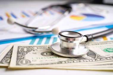 Çizelge ya da grafik kağıdı, Finansal, hesap, istatistik ve iş verileri medikal sağlık kavramı üzerine steteskop ve ABD doları banknotları.