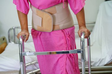 Asya baş ağrısı. Esnek destek kemeri takıp yürüteç takıyor..