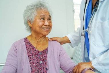Doktor, Asyalı yaşlı kadın engelli hastaya hemşirelik hastanesinde Walker 'la birlikte yürümesi için yardım ediyor..
