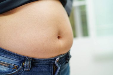 Asyalı kadın şişman göbek gösteriyor. Ofiste kilolu ve obez..