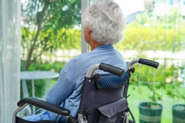 Parkta elektrikli sandalyede oturan Asyalı yaşlı kadın engelli hasta, tıbbi konsept..