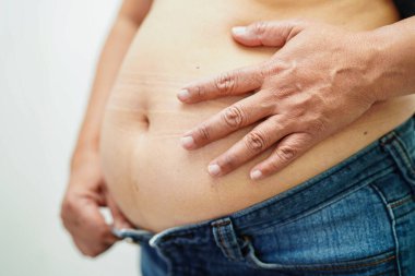 Asyalı kadın şişman göbek gösteriyor. Ofiste kilolu ve obez.