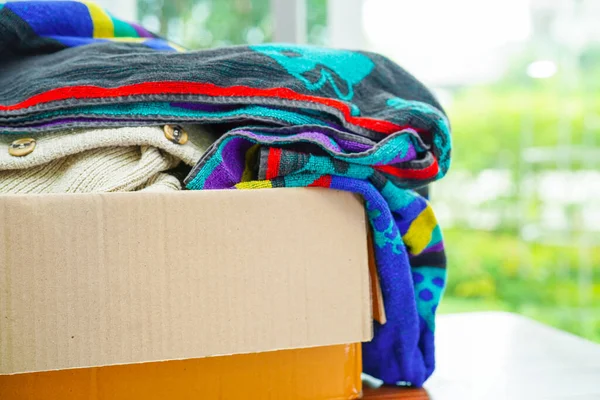 Clothes donations in cardboard box for volunteer.