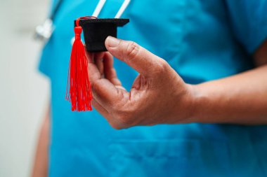 Hastanede elinde mezuniyet şapkası olan Asyalı kadın doktor. Tıp eğitimi konsepti..