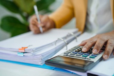 Ofisteki dosya klasöründeki verileri analiz etmek için çalışan ve evrak hazırlayan işadamı.